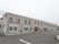 自然豊かな環境に、閑静な住宅街に建つグレーの外壁の鉄骨造2階建の建物。建物前には広々としたスペースがある。