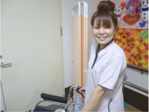 笑顔のスタッフとリハビリ訓練器具