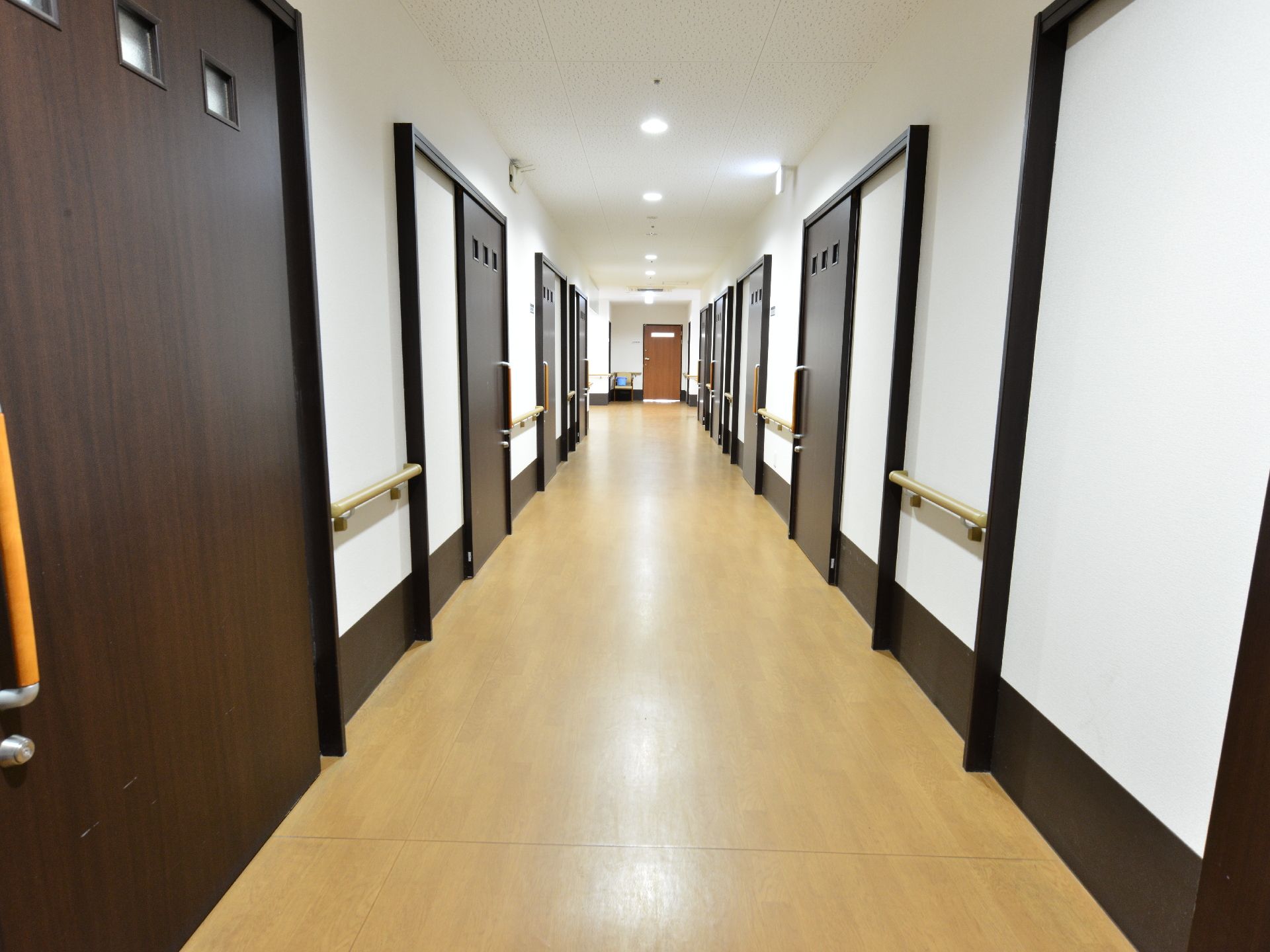 館内のドアはダークブラウンになっている。ドアは引き戸。廊下の両側に手すりが設置されている。照明もあり、明るい。