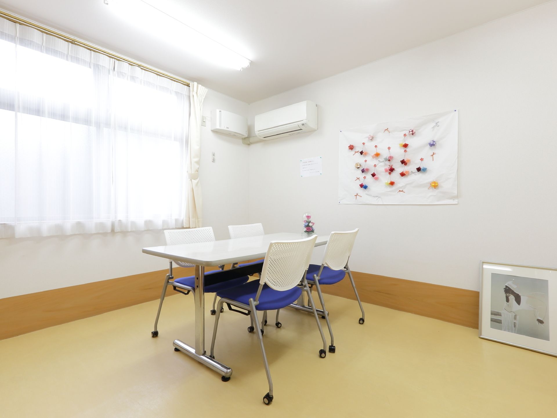 事務椅子4脚と、テーブルが用意されている。多目的室のような空間になっている。壁には装飾が施されている。