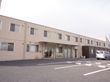 施設の建物は2階建てで、クリーム色の外壁である。玄関前には屋根が備わっている。敷地内に駐車スペースが確保されている。