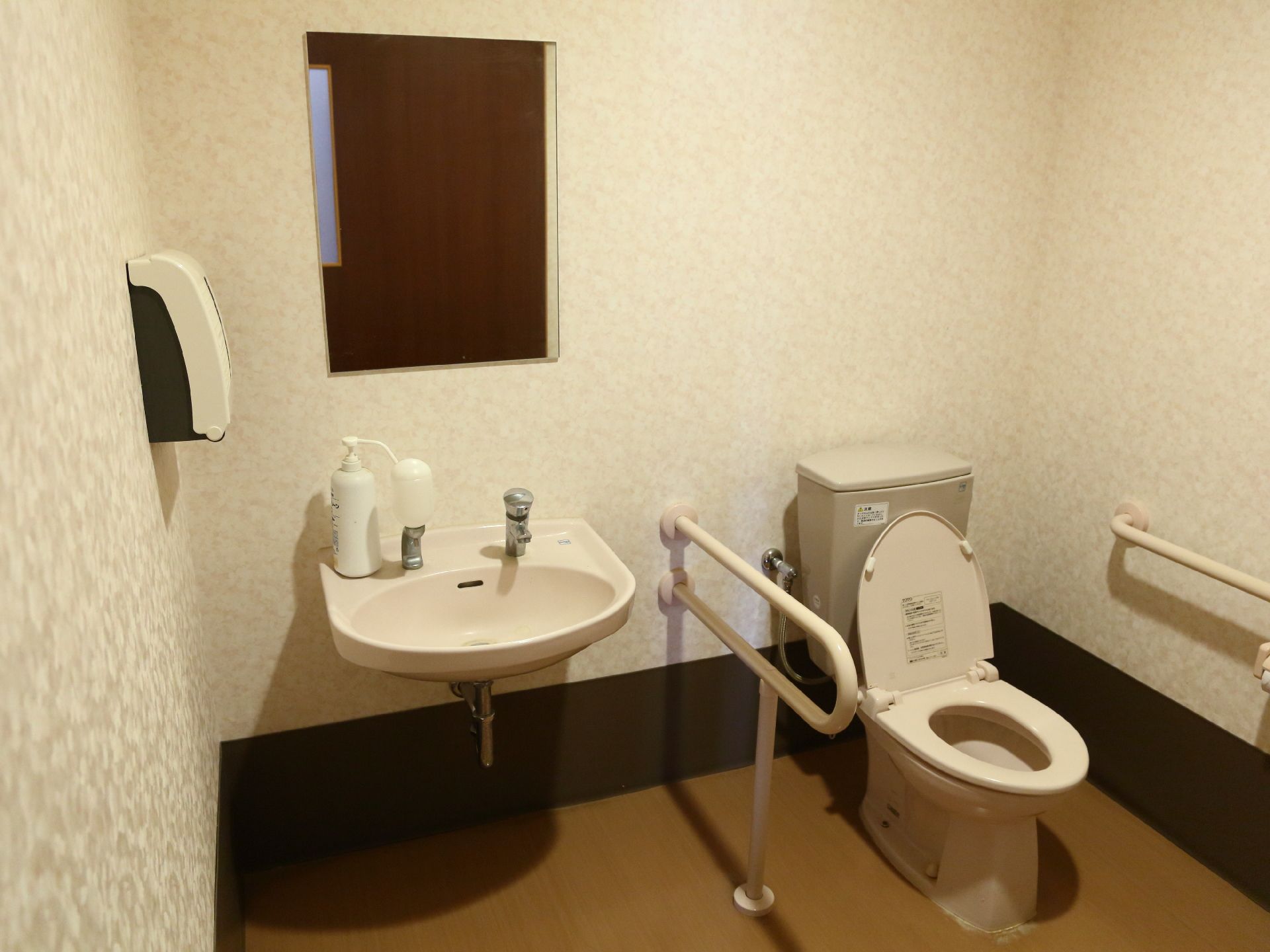 居室内には、トイレも完備されている。手洗い場も一緒になっているタイプで、両脇に手すりがついている。ナースコールもある。