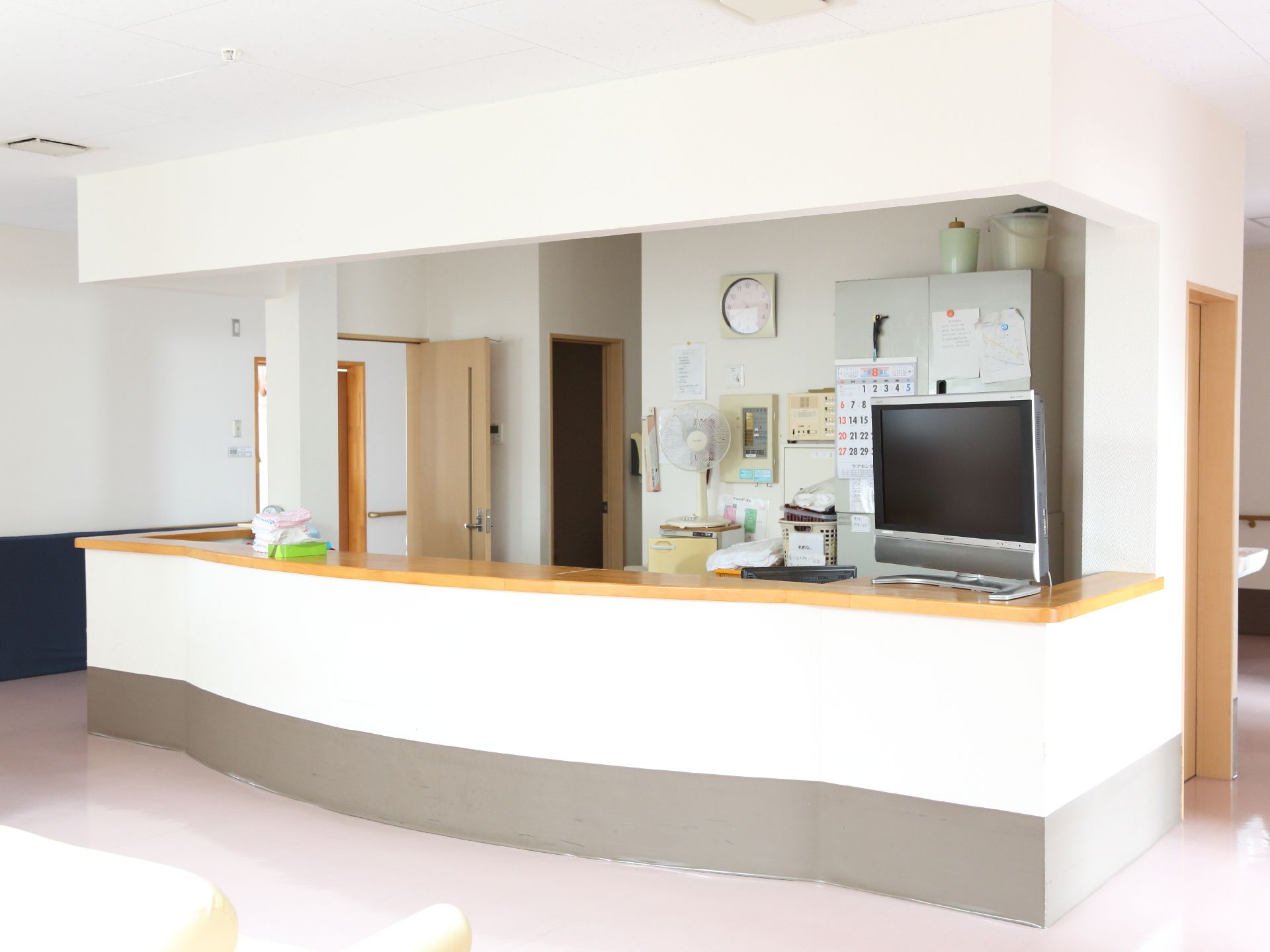 ホールのソファ前には、カウンターがある。カウンターの上には、テレビが置かれている。カウンター内には、扇風機やカレンダーがある。