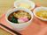 メインはうどんで、かき揚げとかまぼこ、ほうれん草がのっている。付け合せは、卵豆腐で、細かくカットされたフルーツがある。
