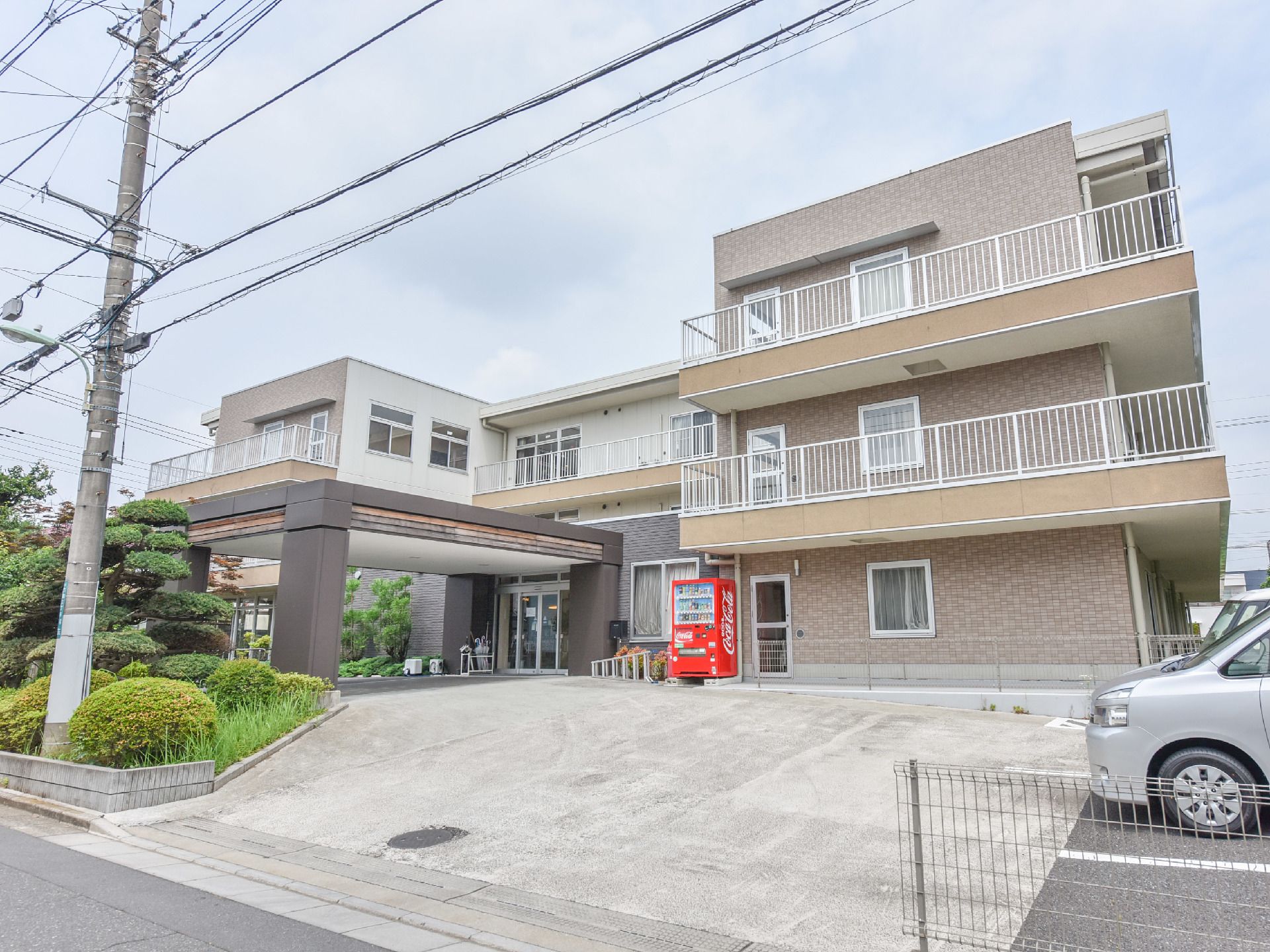 3階建ての建物がこちらの施設である。駐車場も完備されており、剪定された庭木がとても綺麗である。周囲の景観にマッチしている。