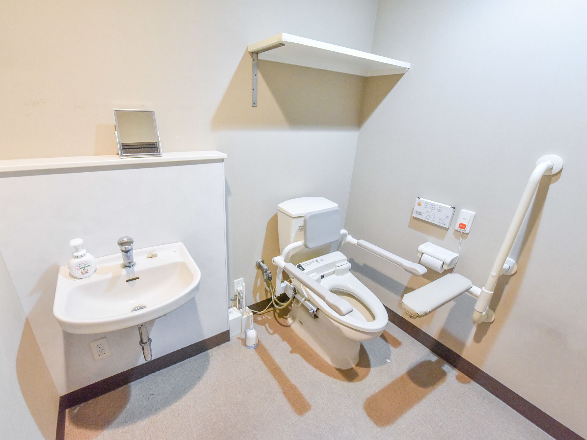 介助用具が付いているトイレには、手すりや背もたれなど要介護の方でも使いやすい仕様になっている。隣には、洗面台があり手洗いも楽にできる。