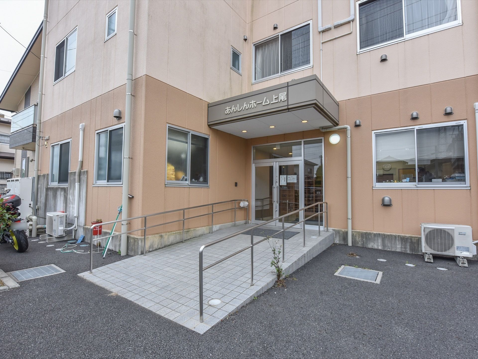 スロープを上がった先の玄関には、横に事務室が設置されており、玄関側に窓があるため、入居者様の入退館の様子をスタッフが確認することができる。