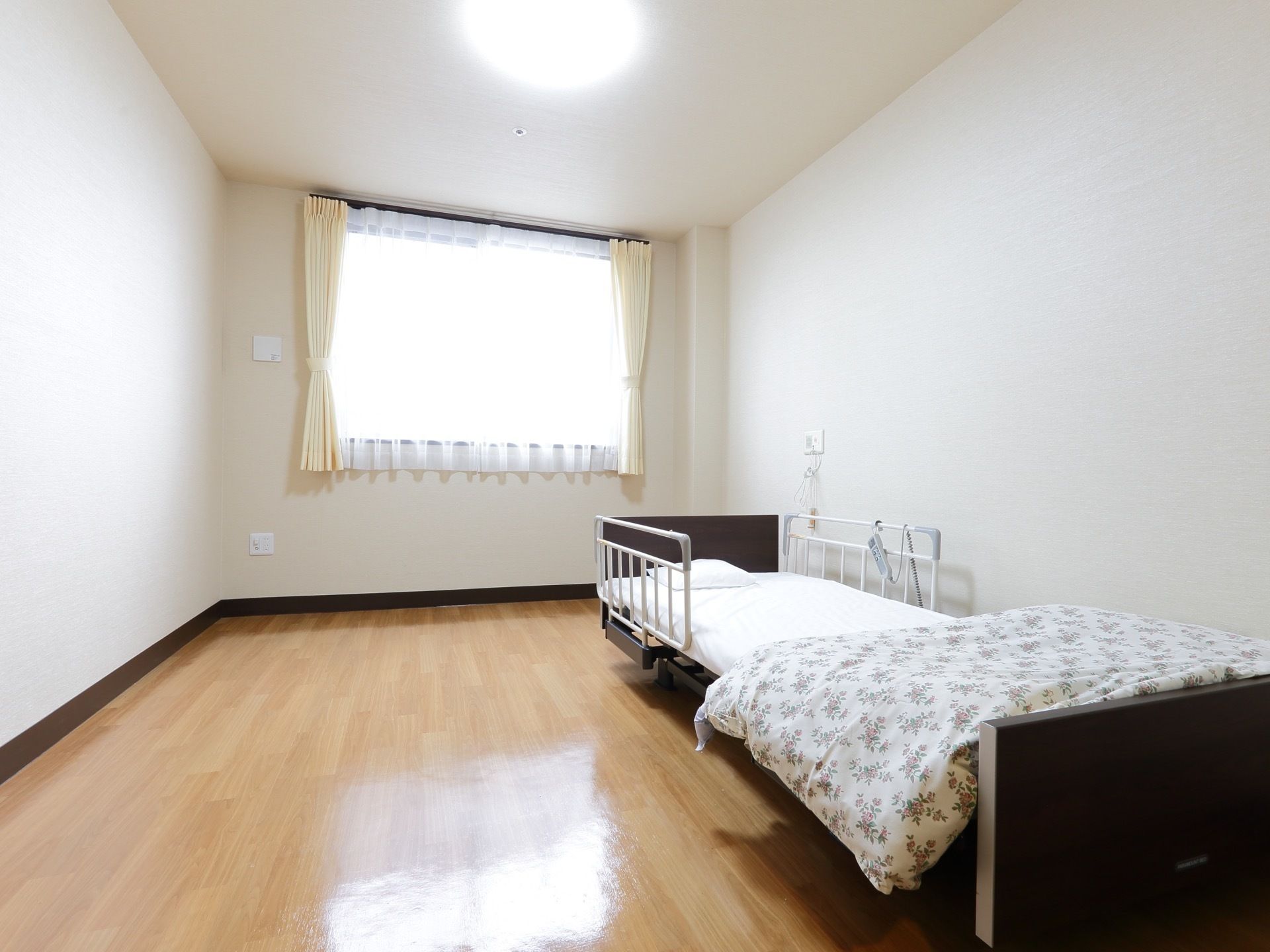 広々とした居室には介護用ベッドを完備している。そばには、非常用呼び出しブザーが備え付けられているのでいざという時には安心である。