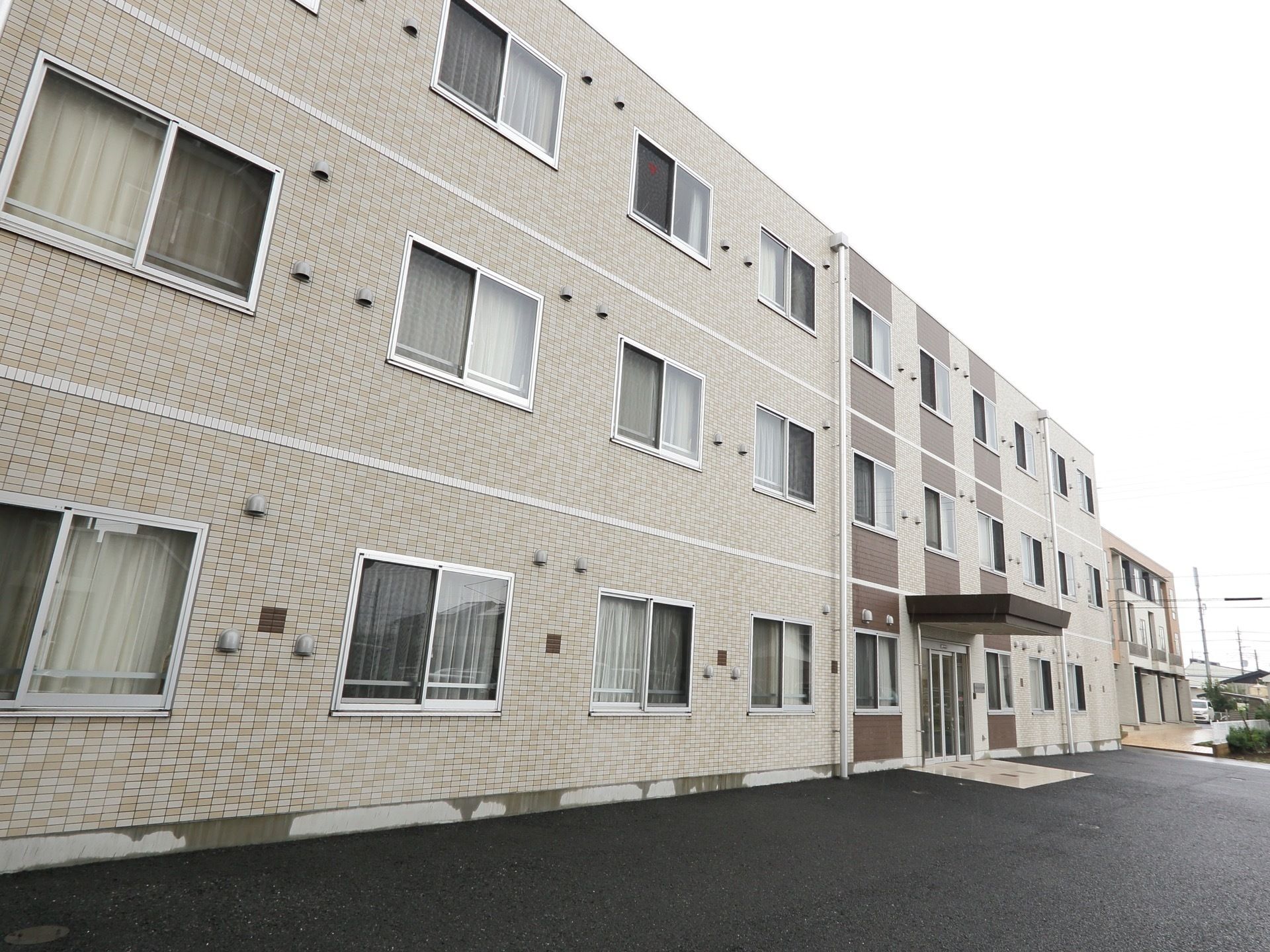 ３階建てのシンプルな建物である。エントランス周辺には駐車場がないので、車が入る心配がなく車いすの方でも安心して通行できる。