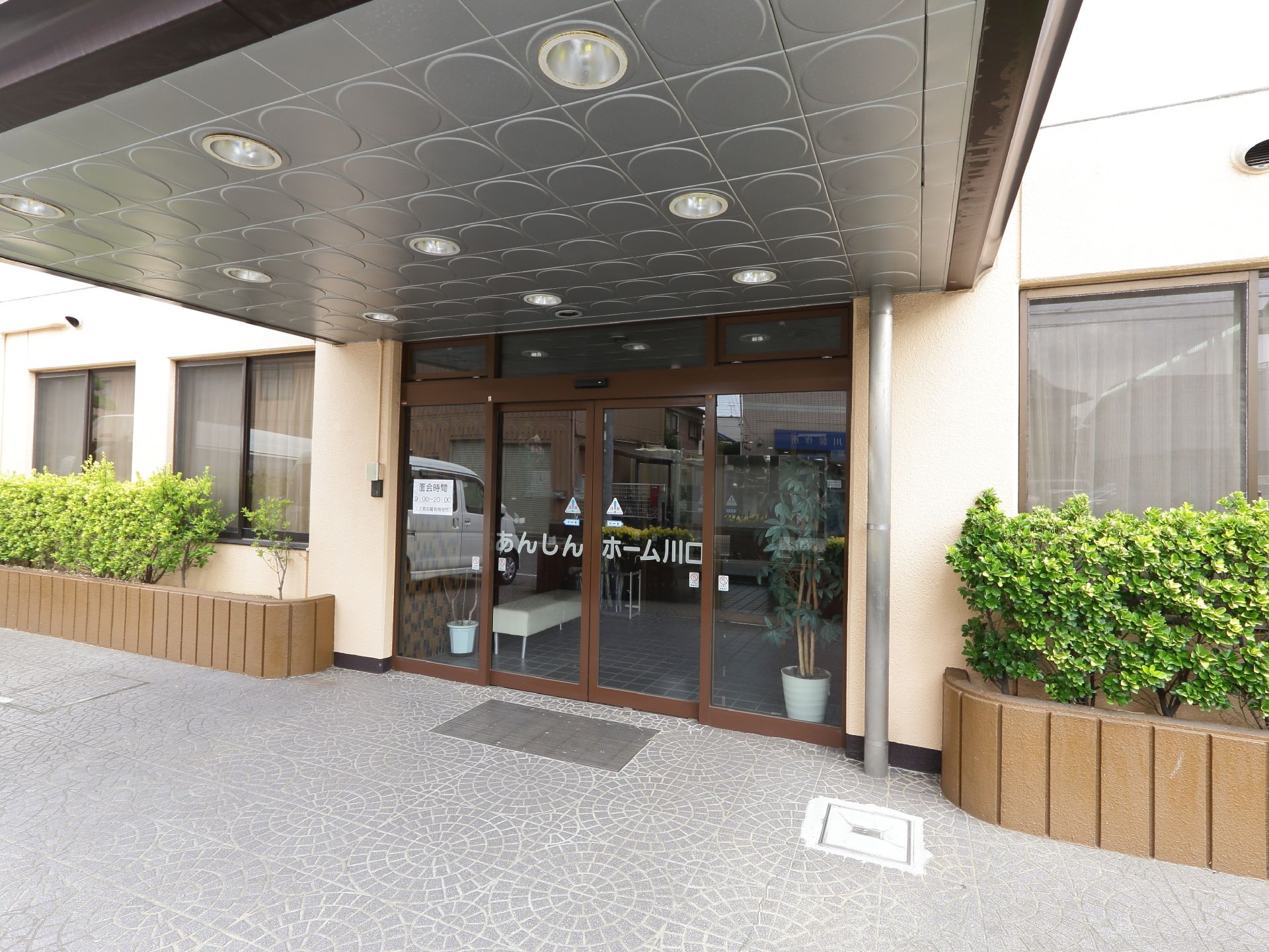 車椅子利用者にも便利な自動ドアの玄関である。簡単に出入りできるのが魅力になっている。植栽の緑が綺麗に映えている。