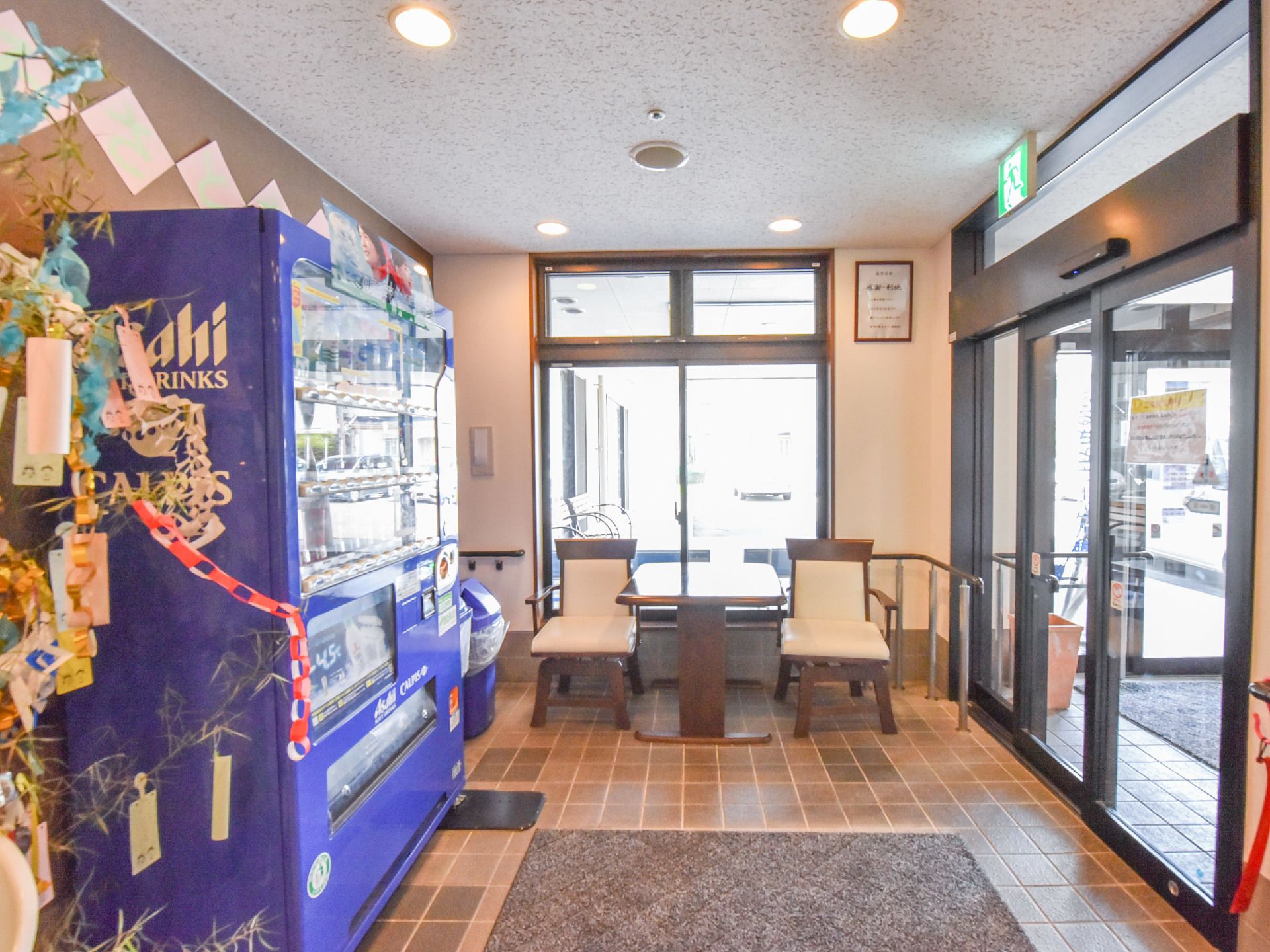 自動販売機と椅子が置かれた玄関では、飲み物を飲みながら、ホッと一息つける最適な休憩スポットである。月の行事ごとは七夕で笹飾りが飾ってある。