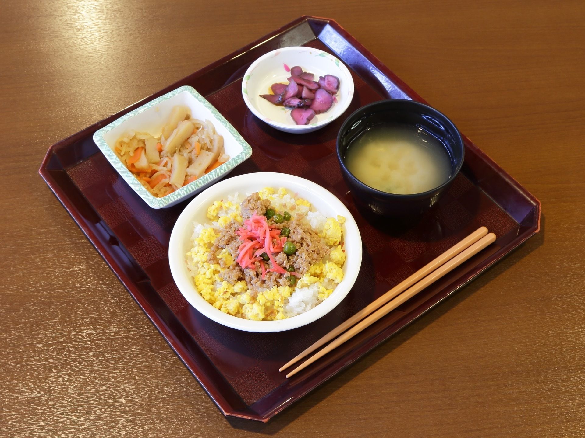 食事の一例である。主食に２色のそぼろごはんと味噌汁、煮物と漬け物がある。とても彩りがきれいで、高齢者が食べやすいように工夫してある。