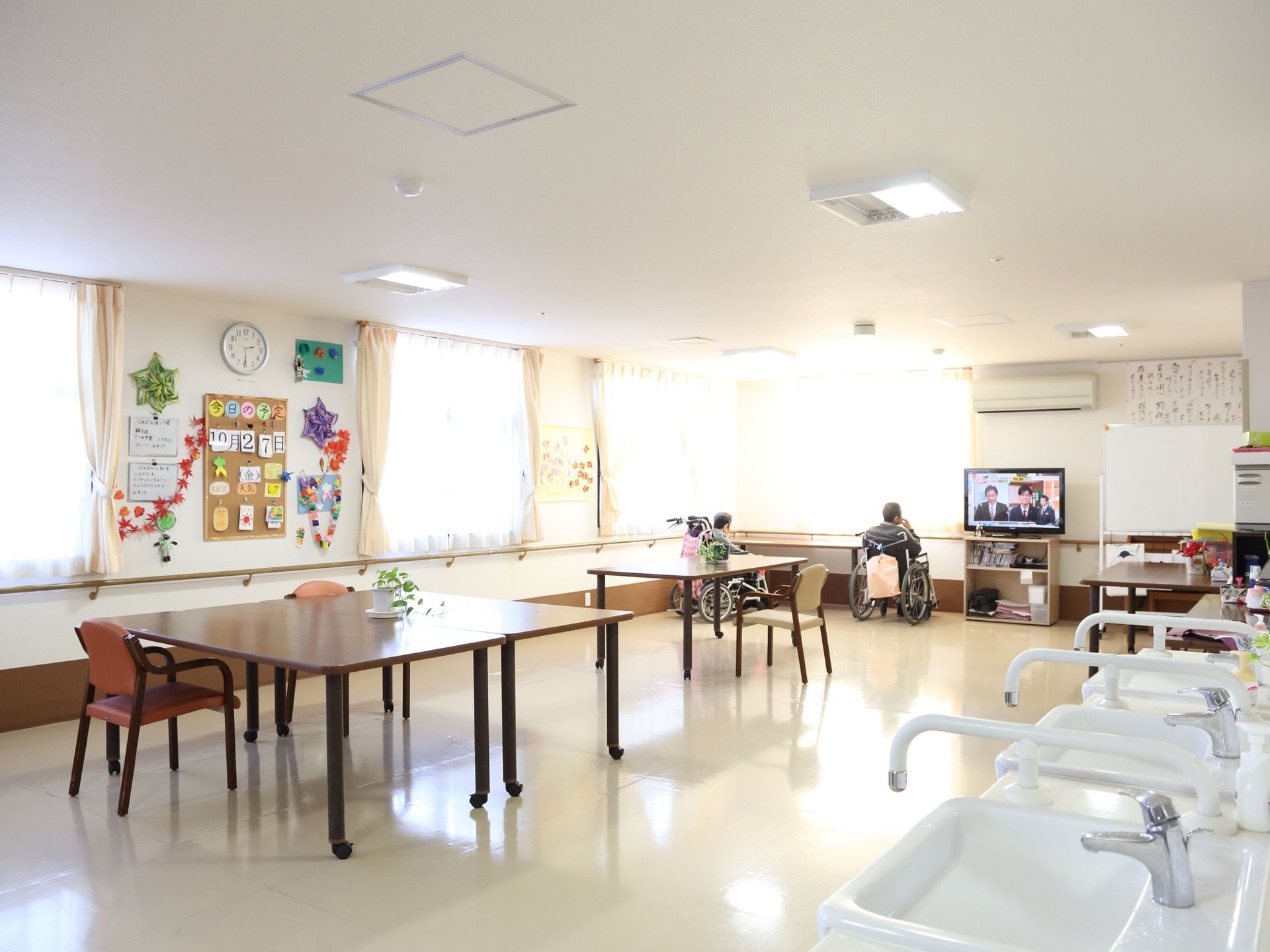広い共有スペースの様子。壁には折り紙などで作った飾りなどが取り付けられ、その日の日付が大きく掲示板に貼られている。