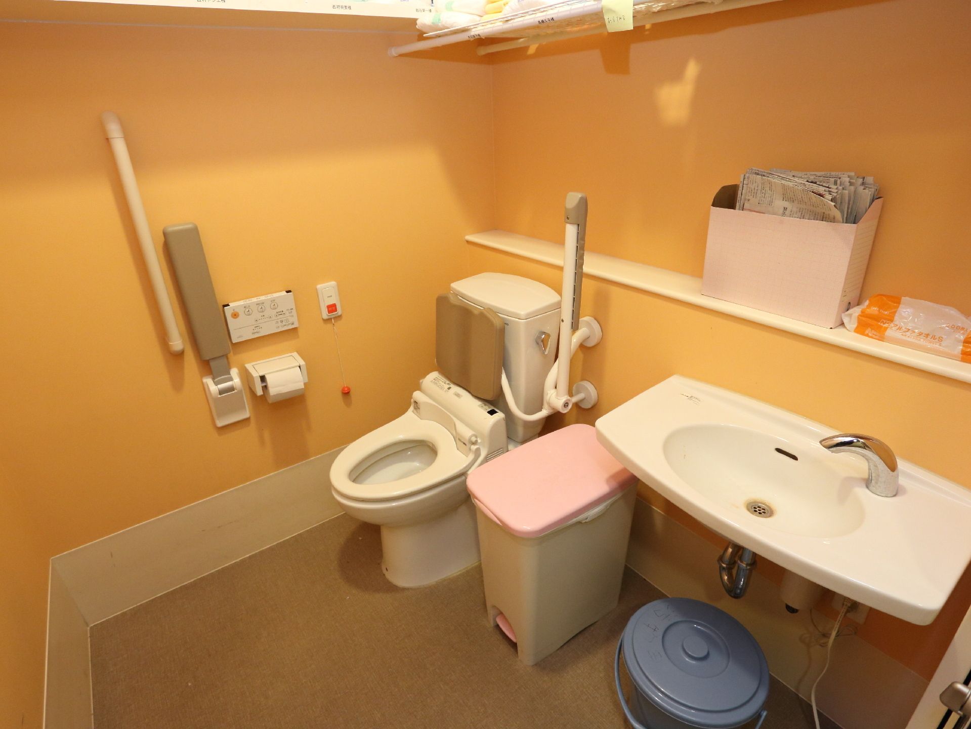 広々としたトイレには、緊急呼び出しブザーや可動式の手すり、背もたれ、前方ボードなど利用者が安心安全に使用できる。