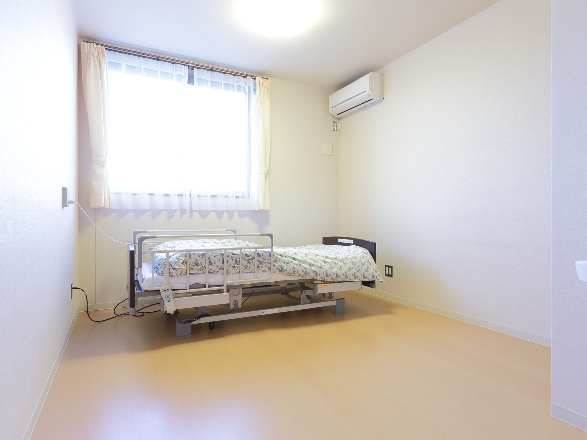 居室はフローリング床のワンルーム。ベッドを設置しても広さに余裕がある。腰高の窓があり、明るいお部屋。