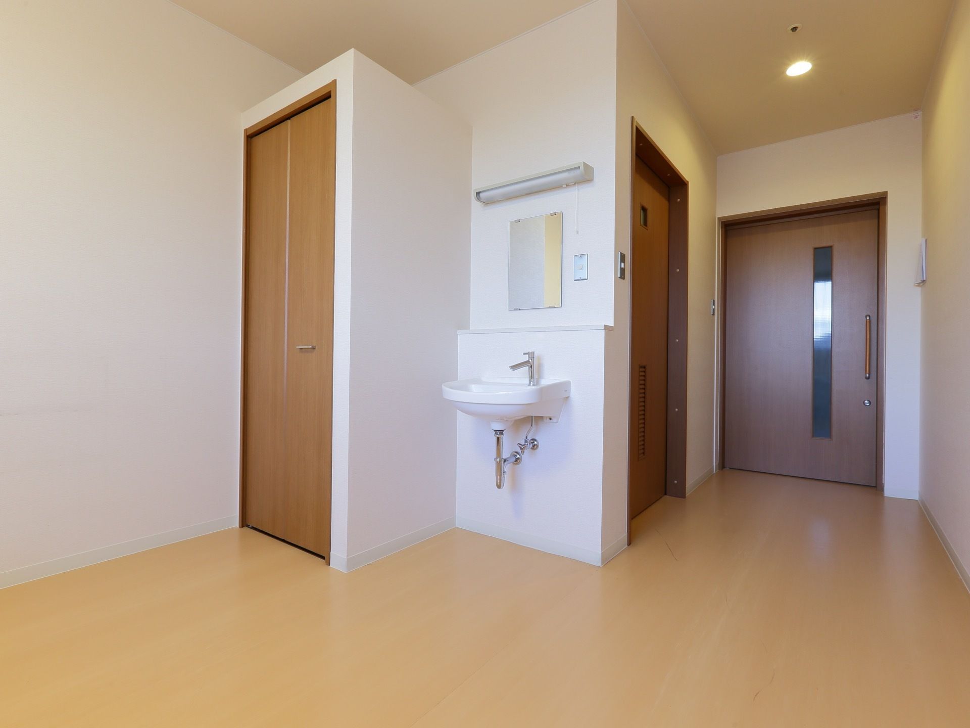 居室の壁は白、床は明るい色のフローリング。入口は大きく開く引き戸になっている。各部屋に収納と洗面台が設置されている。
