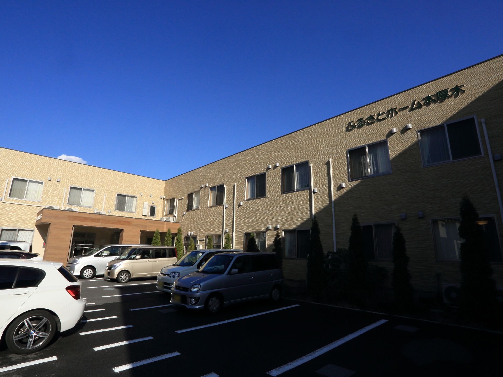 建物の前に設けられた駐車場は大きく何台も停める事ができる。建物は２階建てで駐車場を取り囲むように建てられている。