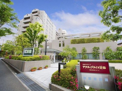 植込みやテラスに多くの草木が植えられた、白色の大きな建物