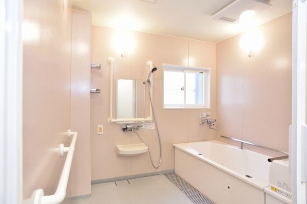 洋室の居室でエアコンが完備されている。室内には介護用ベッドが置かれ、洗面台や収納スペースの設備が備わっている。