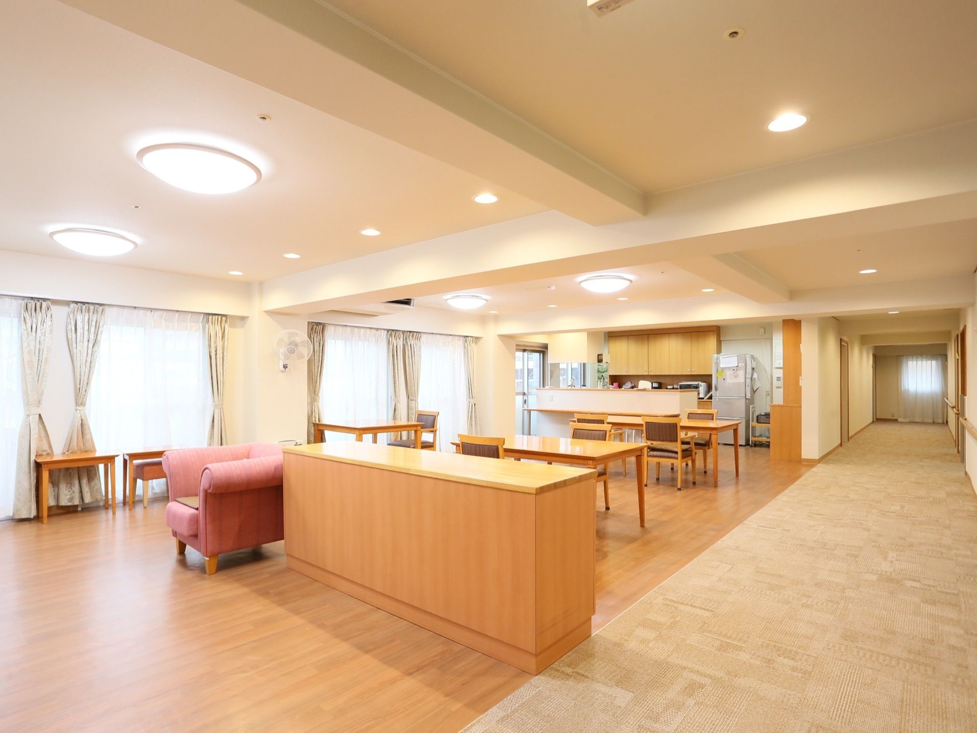 キッチンの向かいにあり、入居者様の健康状態を確認しながら調理できる。テーブルの間隔が十分確保されている。