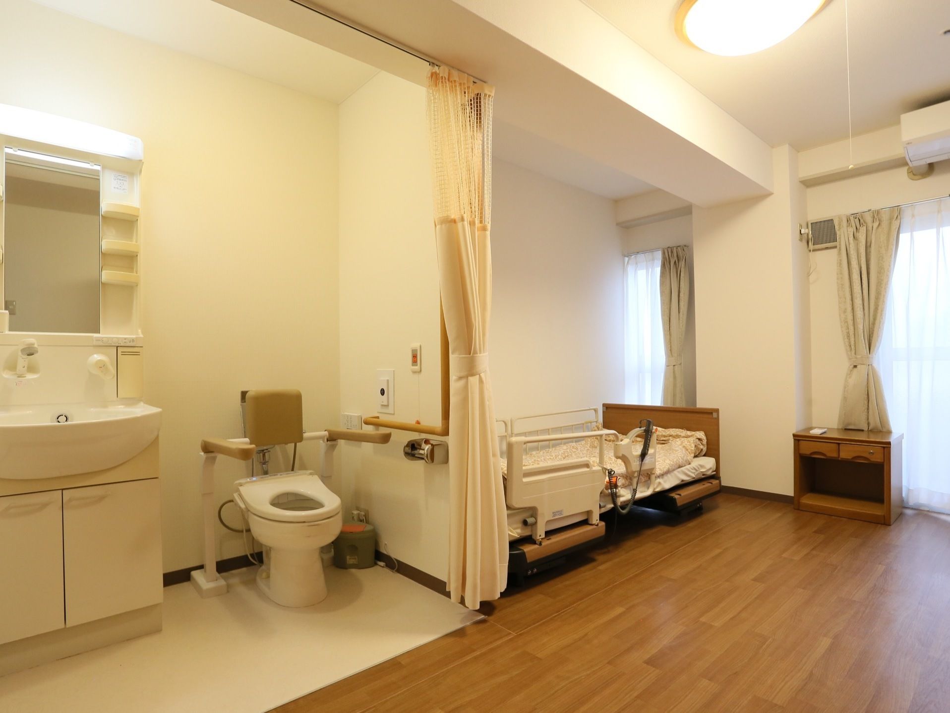 トイレには、介助用の手すりと背もたれが備わっている。壁にも手すりがあり、防犯ブザーが用意されている。