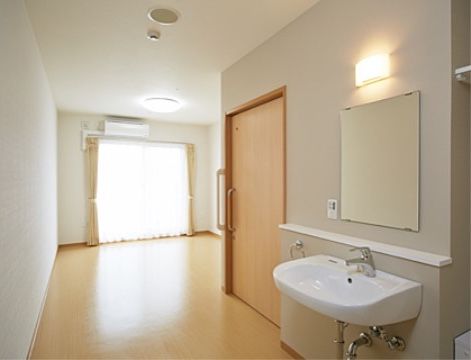 室内に入ってすぐのところに洗面台を設置しており、トイレの個室の奥に居住スペースがある。掃き出し窓が設置された明るい室内である。