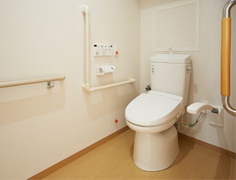 居室に設置されている、引き戸で仕切られたトイレである。手すりや緊急用の呼出ボタンも、設置されている。