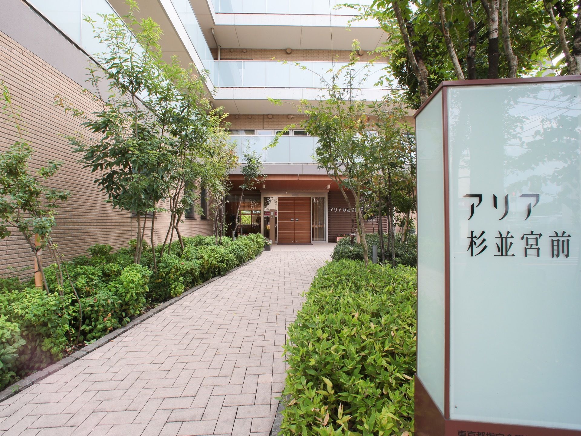 緑の木々に囲まれて自然を感じられるマンションエントランス