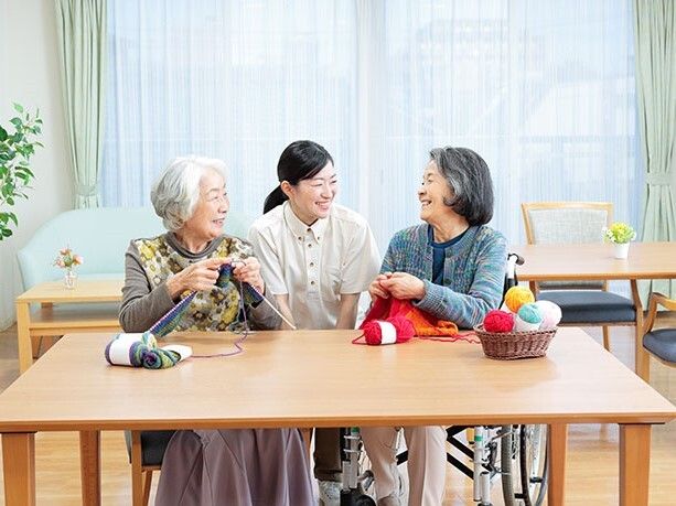屋外の緑地でベンチに座る女性と、その隣で車椅子に乗っている男性