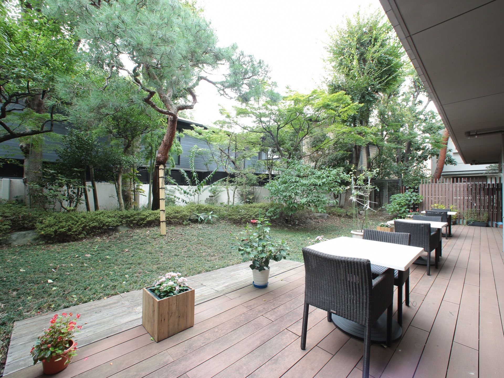 さまざまな木々が植えられた庭にあるウッドデッキのテラス席