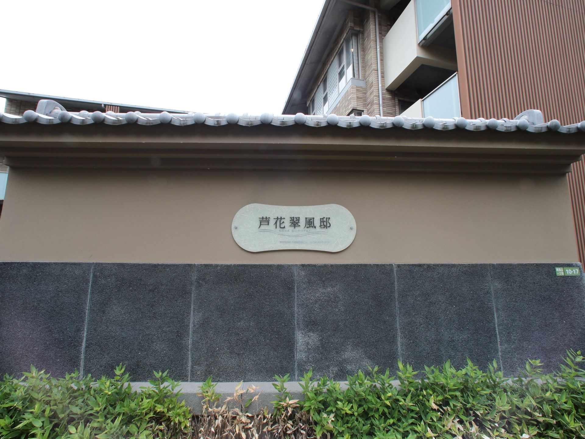 瓦屋根で、シンプルなデザインの看板が掛けられた施設の外壁
