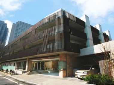 施設外観は黒く、1階部分には白い車が1台止められている。入口には階段と手すり付きのスロープが設置されている。