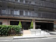 施設全体は黒い柵のようなもので囲まれた作りになっている。周りには植え込みがある。階段の横にはスロープも設置されている。