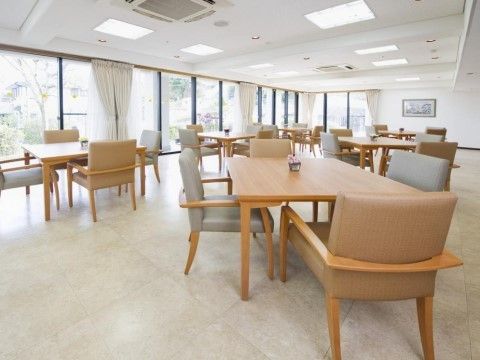 大きな窓に囲まれたダイニングスペースからは庭の緑を眺めることができる。全体に白を基調とした清潔感あふれるスペース。