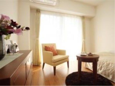 突き当りに大きな掃き出し窓があり、上にエアコンが設置してある。ベッドは一方の壁に沿って置かれ、反対の壁には整理ダンスが置かれている。