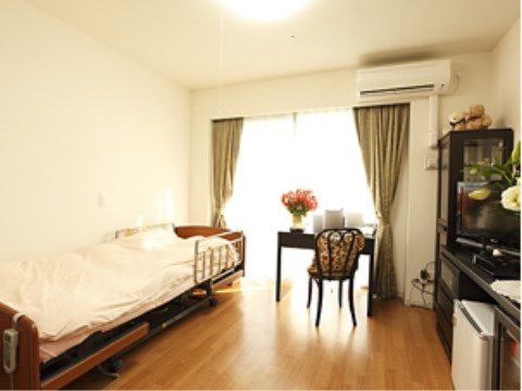 シックな家具で統一された部屋は入居者様に落ち着きのある空間を提供する。無機質になりがちな電動ベッドのデザインにも、そのこだわりが表れている。