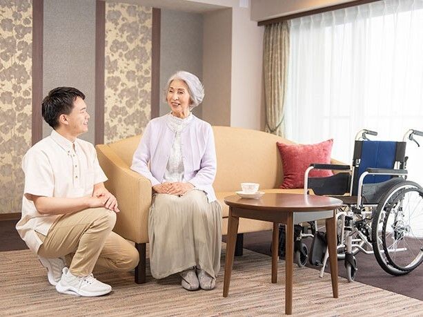 晴れた日に屋外のベンチで休憩する女性と車椅子に乗った男性