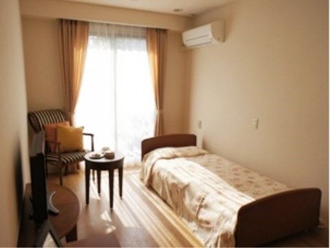 居室は日当たりが良い環境である。ベッド、テーブル、椅子、テレビ、エアコンなど生活に必要な物が完備されている。