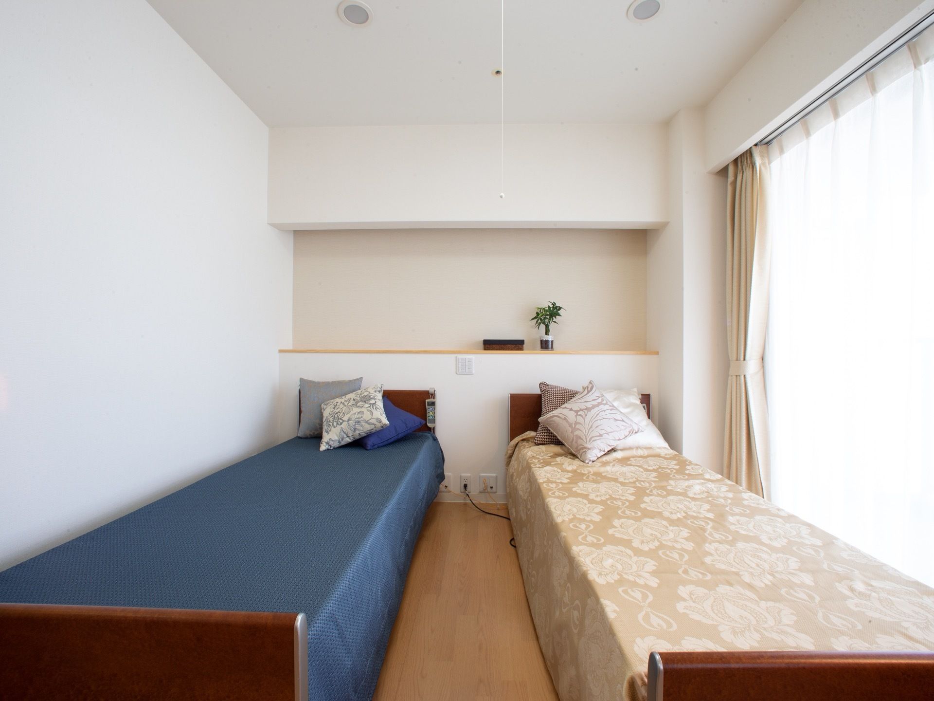 白を基調とした部屋に並んだピンクベージューとネイビーブルーのベッド