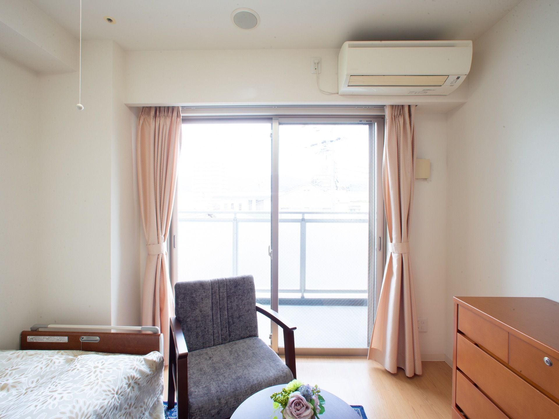 ベッドとチェアー、タンスのある明るいワンルームのお部屋