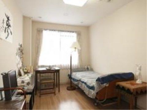 フローリングの床と白い壁のシンプルな居室には、落着いた木目調の調度品が置かれ、壁には大きな書が飾られている。
