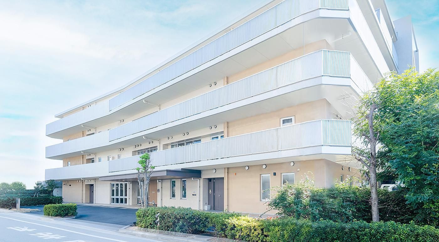 ４階建ての日当たりの良い大きなグループホームである。目の前には横断歩道や、たくさんの草木が植えられた花壇が設置されている。