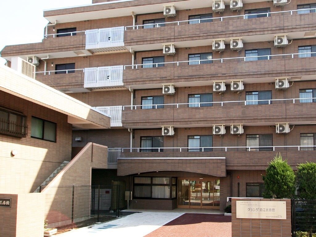 施設の建物の外観である。建物は５階建てで、壁の色はベージュ系である。居室にはベランダが設置されている。