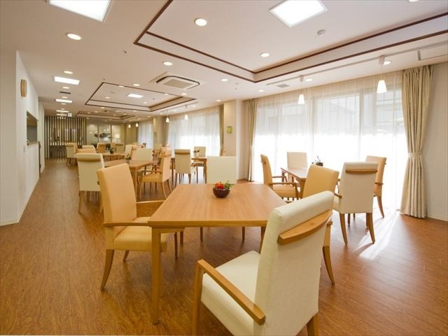 複数のテーブルと椅子が置かれ、多くの照明で照らされた食堂