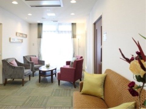 カーペット敷きのエントランスにはソファーが並べられている。大きな窓から明るい日差しが差し込んでいる。