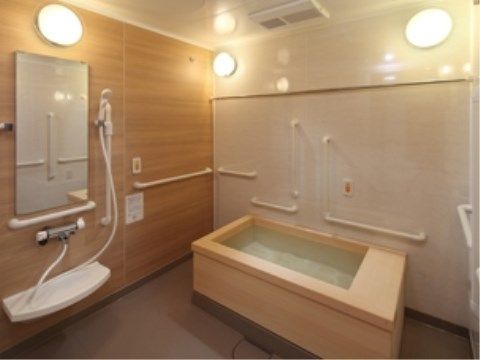 木のぬくもりが感じられる広い浴室。多数の手すりと呼び出しボタンが２つ備え付けられており、一人でも安心して入浴することができる。