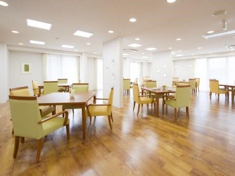 白い天井と壁、木目調の床が印象的なダイニングルームである。黄色い背もたれの椅子が明るい雰囲気を醸し出している。