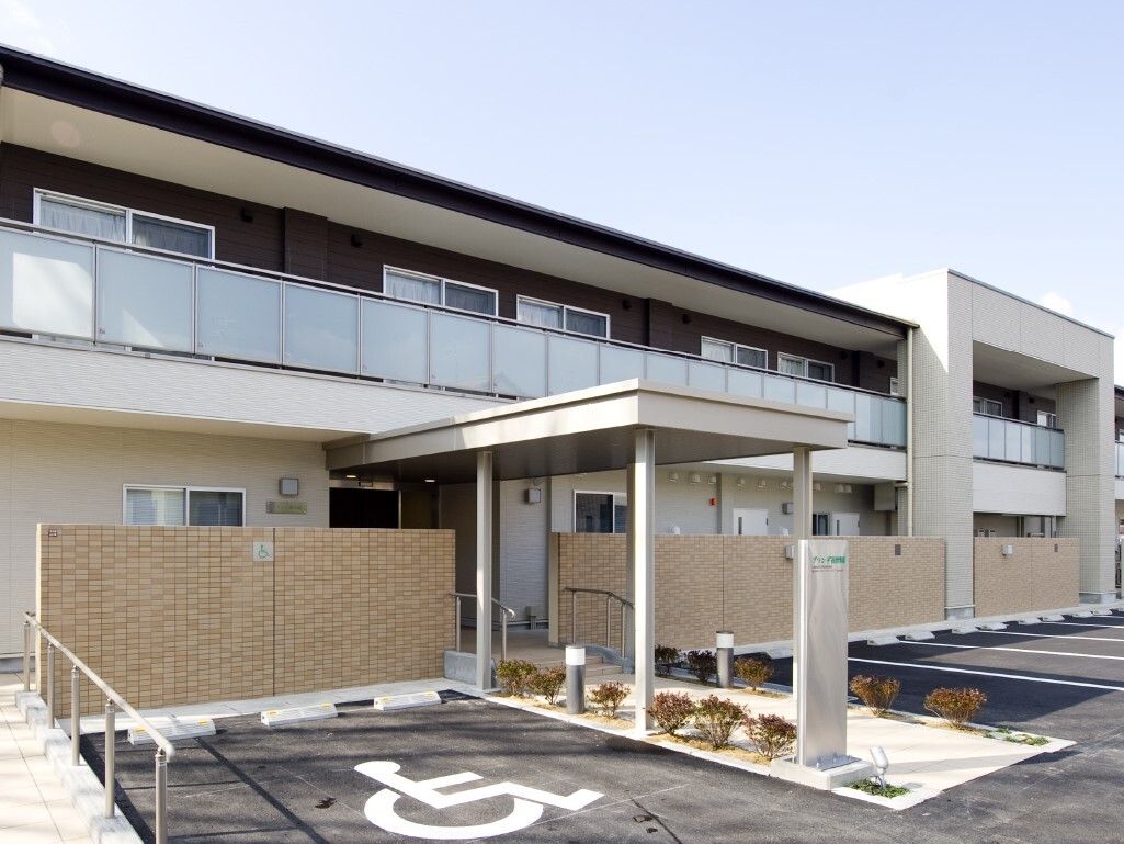 ２階建ての賃貸住宅のような雰囲気の建物である。玄関前には駐車スペースが大きくとられているので、車で来られる方も安心である。