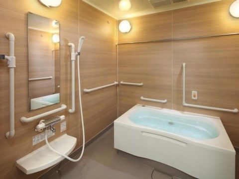 木目調の壁が特徴の広々とした浴室は、あらゆる箇所に手すりが設置されており、お一人でのご利用も安心できる。