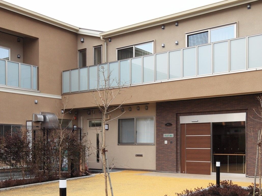 Ｌ字型の2階建ての施設の横には、ご家族様などがいつでも利用することができる広い駐車場が用意されている。